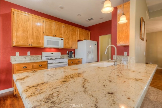 kitchen with kitchen peninsula, white appliances, sink, dark hardwood / wood-style floors, and hanging light fixtures