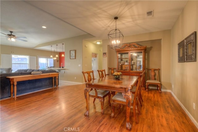 dining area featuring wood-type flooring and ceiling fan with notable chandelier