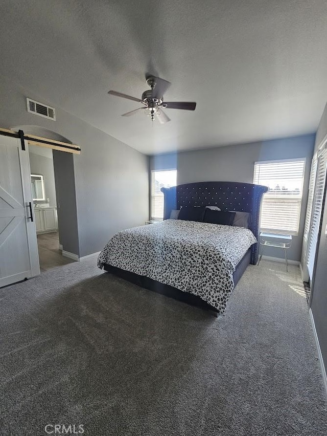 bedroom featuring carpet flooring, ceiling fan, a barn door, a textured ceiling, and connected bathroom