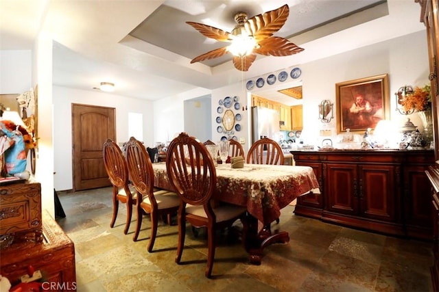 dining space with a tray ceiling and ceiling fan