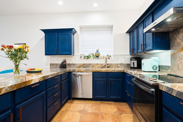 kitchen with appliances with stainless steel finishes, blue cabinets, light stone countertops, and wall chimney range hood