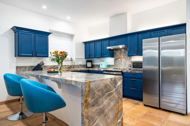 kitchen with tasteful backsplash, a kitchen breakfast bar, kitchen peninsula, stainless steel appliances, and blue cabinetry