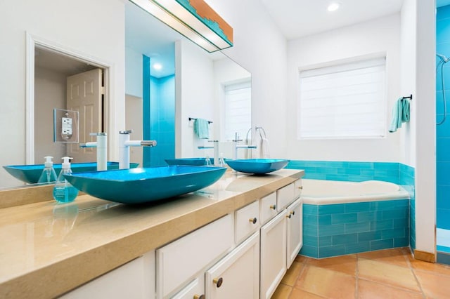 bathroom featuring tile patterned flooring, vanity, and tiled bath