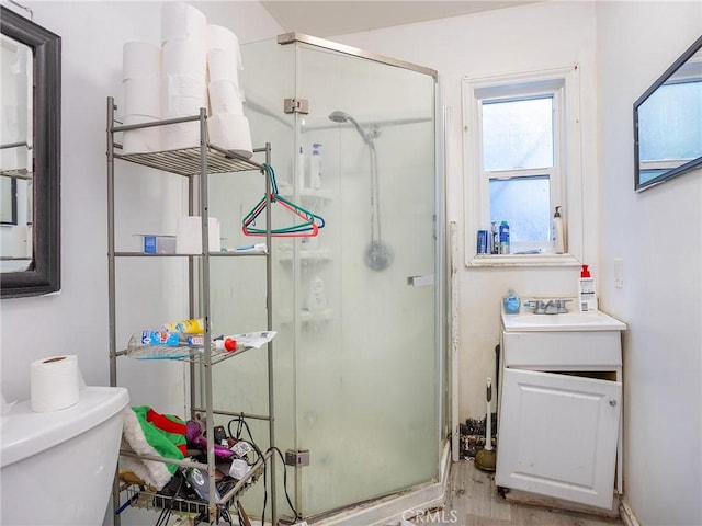 bathroom featuring vanity, toilet, and a shower with shower door