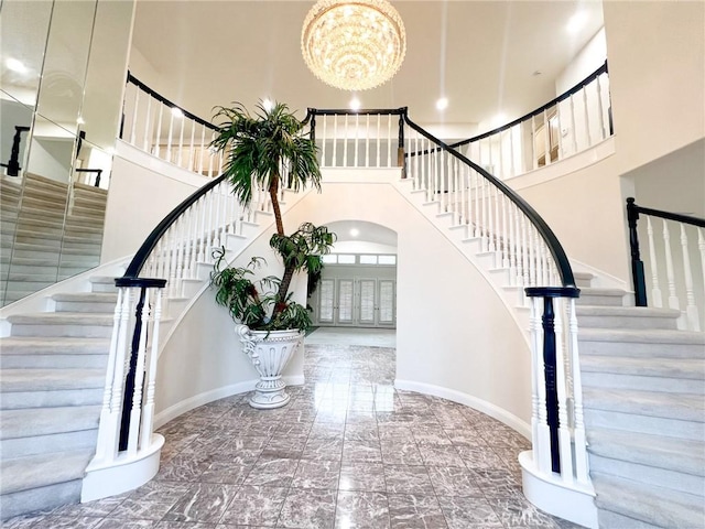 staircase with a notable chandelier and a high ceiling