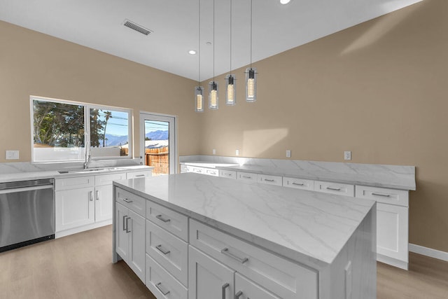 kitchen with dishwasher, a center island, white cabinets, light stone countertops, and light wood-type flooring