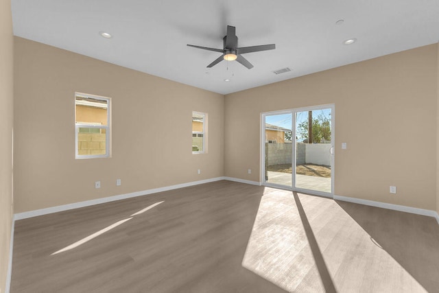 spare room featuring dark hardwood / wood-style flooring, ceiling fan, and plenty of natural light