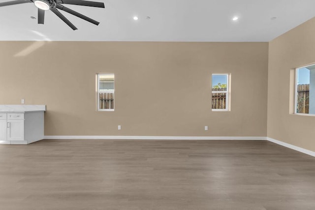 unfurnished living room with ceiling fan, light wood-type flooring, and a wealth of natural light