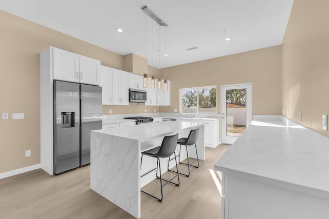 kitchen with white cabinetry, a center island, decorative light fixtures, and appliances with stainless steel finishes