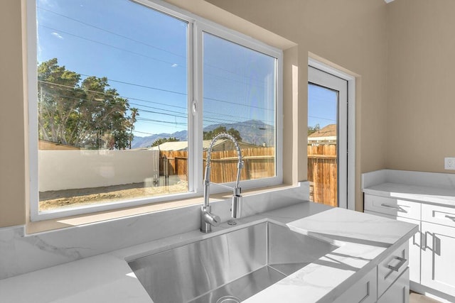 interior space featuring white cabinets, light stone counters, and sink