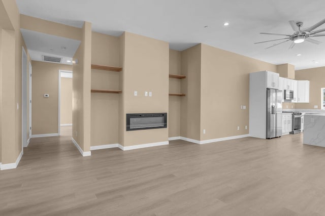 unfurnished living room featuring heating unit, ceiling fan, built in features, and light hardwood / wood-style floors