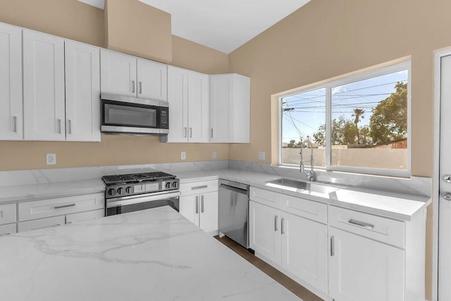 kitchen with white cabinetry, light stone countertops, sink, and stainless steel appliances