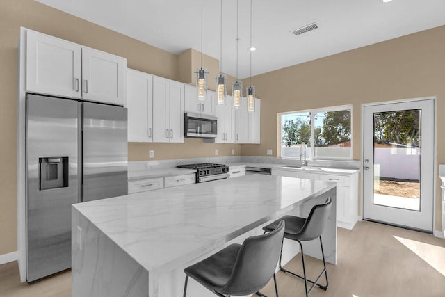 kitchen with a kitchen island, light wood-type flooring, white cabinetry, and stainless steel appliances