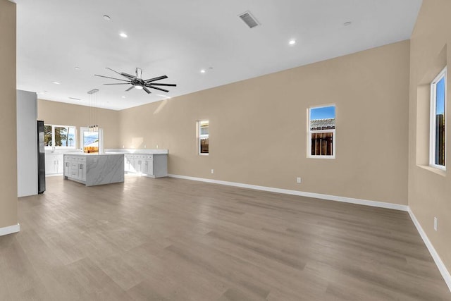 unfurnished living room featuring ceiling fan and light wood-type flooring