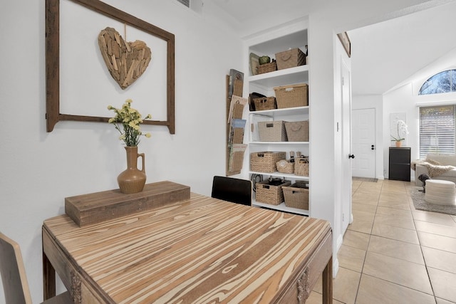 dining room featuring built in features, light tile patterned flooring, and lofted ceiling