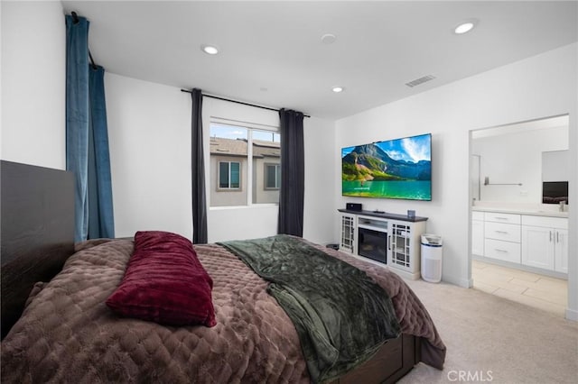 carpeted bedroom featuring ensuite bathroom and sink