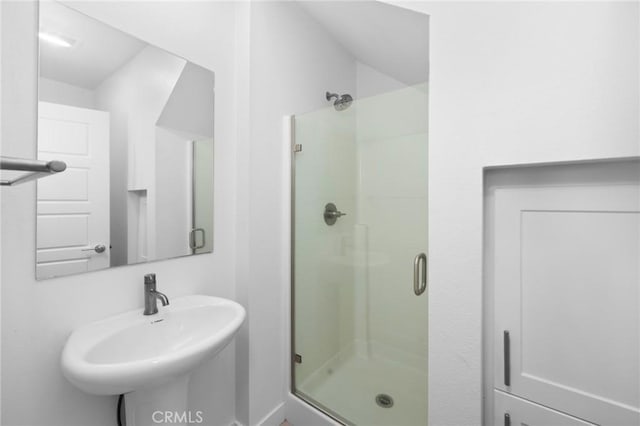 bathroom with a shower with door and sink