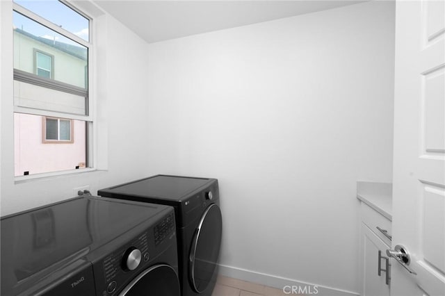 washroom featuring washing machine and clothes dryer, light tile patterned floors, and cabinets