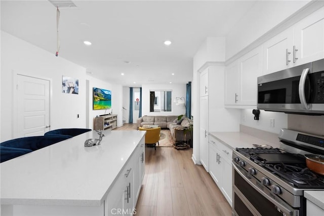 kitchen featuring white cabinetry, light hardwood / wood-style flooring, a kitchen island, and appliances with stainless steel finishes