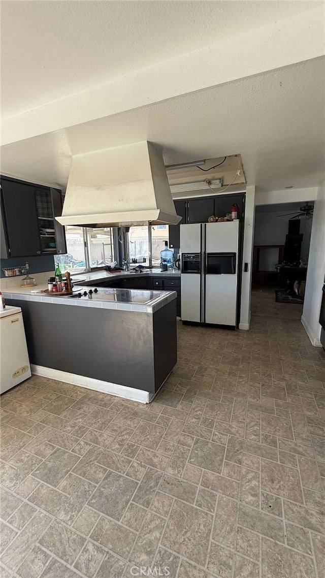 7002 Valentine Dr, Huntington Beach, CA 92647 - kitchen with a peninsula, white refrigerator with ice dispenser, dark cabinetry, and premium range hood