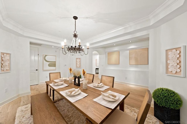 dining room with a notable chandelier, crown molding, and light hardwood / wood-style flooring