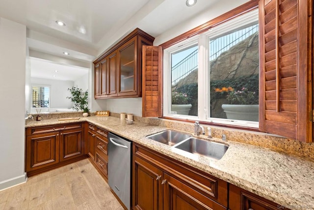 kitchen with dishwasher, light stone counters, sink, and light hardwood / wood-style flooring