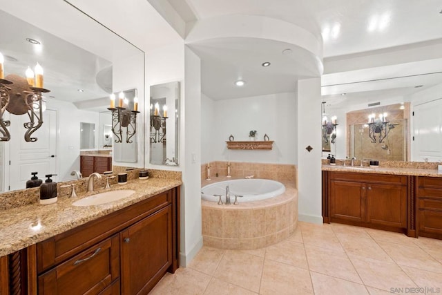 bathroom with tile patterned flooring, vanity, and tiled bath