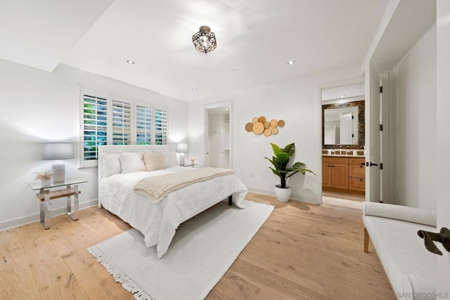 bedroom with ensuite bathroom, light hardwood / wood-style floors, and a spacious closet