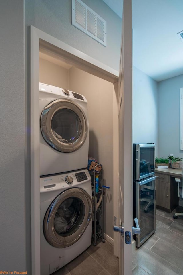 clothes washing area with stacked washer and dryer and light tile patterned floors