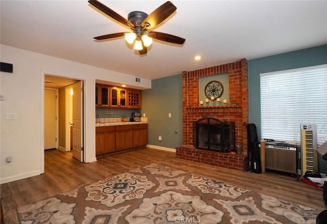 unfurnished living room featuring ceiling fan, dark hardwood / wood-style flooring, and a fireplace