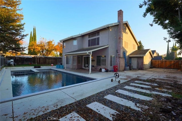 rear view of house featuring a patio and a fenced in pool