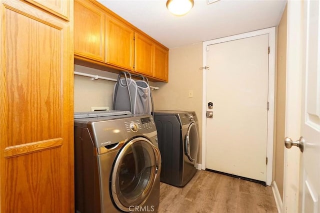 clothes washing area featuring washer and dryer, cabinets, and light wood-type flooring