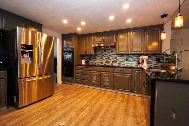 kitchen featuring stainless steel fridge with ice dispenser, black double oven, light hardwood / wood-style flooring, and sink