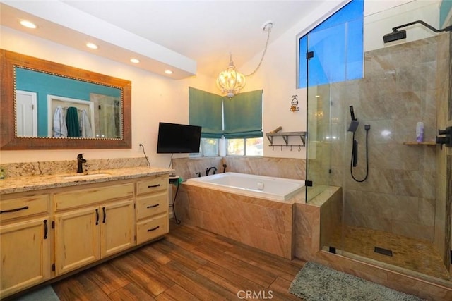 bathroom with hardwood / wood-style floors, vanity, shower with separate bathtub, and an inviting chandelier