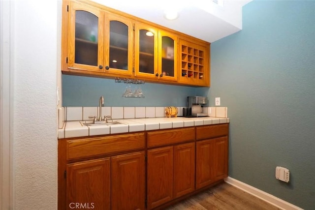 bar featuring dark hardwood / wood-style flooring, tile counters, and sink