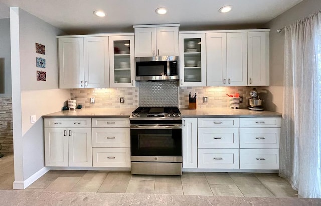 kitchen with appliances with stainless steel finishes, white cabinets, and tasteful backsplash