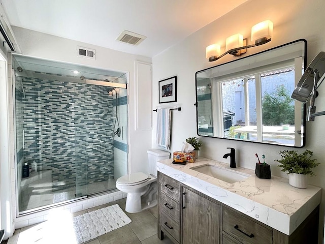 bathroom with a shower with shower door, toilet, vanity, and tile patterned flooring