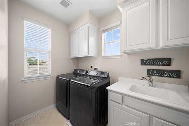 washroom featuring cabinets, a healthy amount of sunlight, washing machine and dryer, and sink