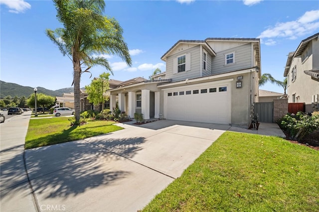 front facade featuring a mountain view, a front lawn, and a garage