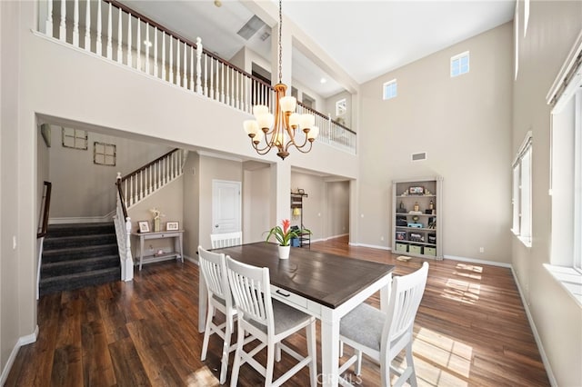 dining space featuring a chandelier, a towering ceiling, and dark wood-type flooring