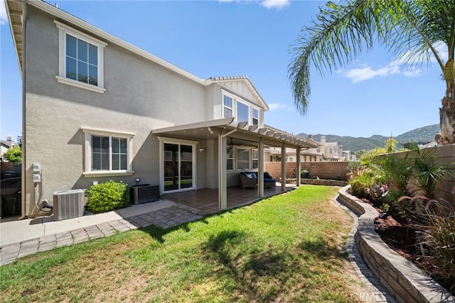 back of property with a pergola, central air condition unit, a mountain view, a patio, and a lawn