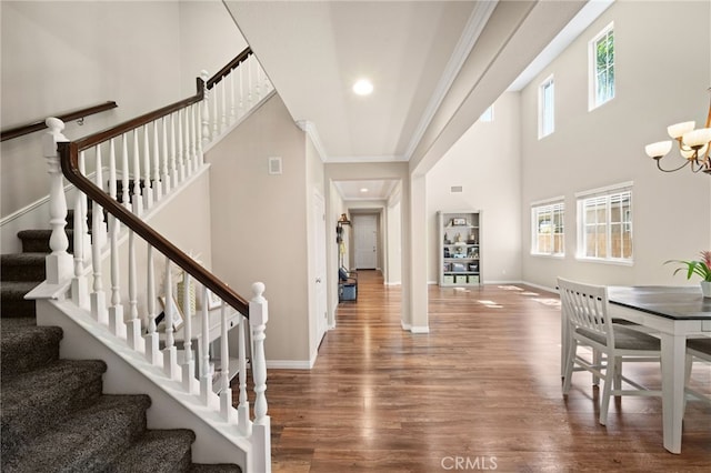 foyer featuring hardwood / wood-style flooring, an inviting chandelier, plenty of natural light, and ornamental molding