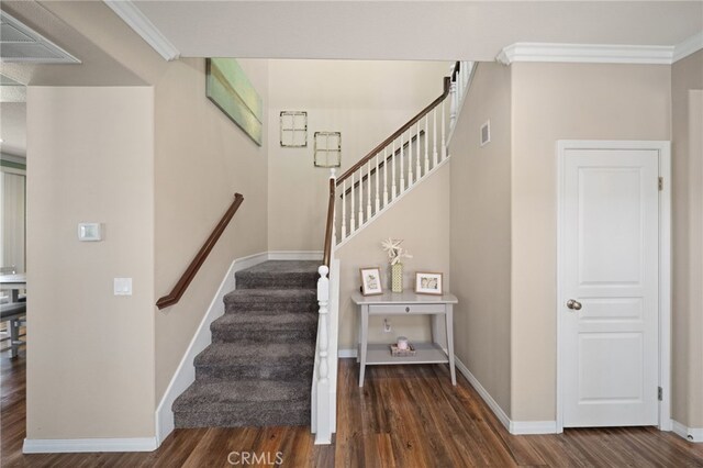 staircase with wood-type flooring and crown molding