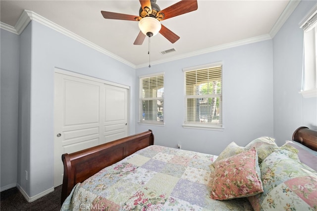 bedroom featuring ceiling fan, dark carpet, crown molding, and a closet