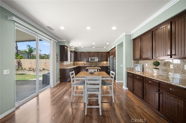 kitchen with dark brown cabinetry, stainless steel appliances, dark wood-type flooring, crown molding, and a kitchen island