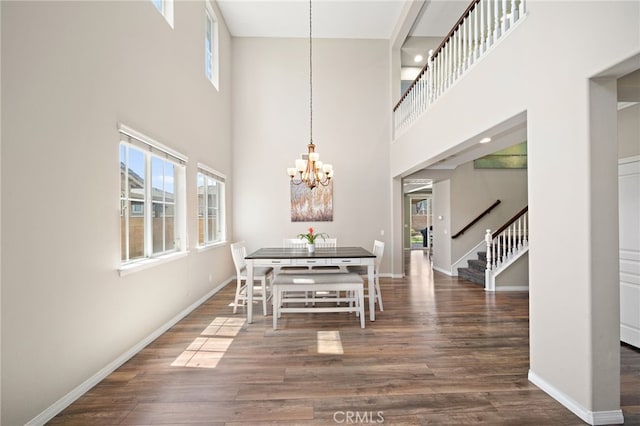 dining room with dark hardwood / wood-style flooring, a chandelier, and a high ceiling