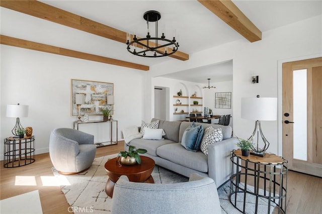 living room with beamed ceiling, plenty of natural light, light hardwood / wood-style floors, and an inviting chandelier