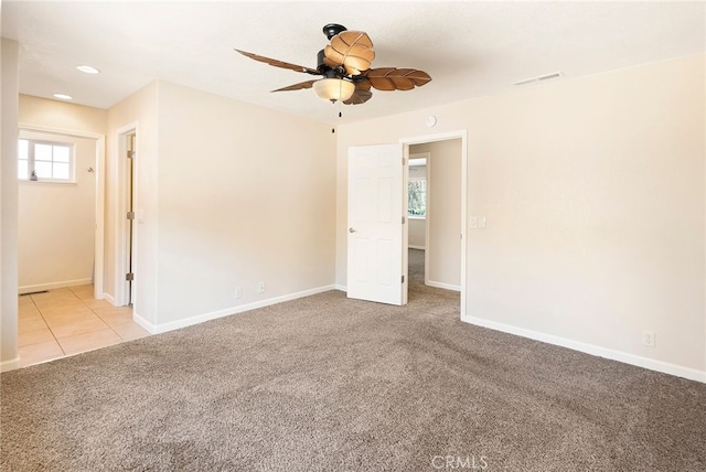 spare room featuring ceiling fan, a wealth of natural light, and light carpet