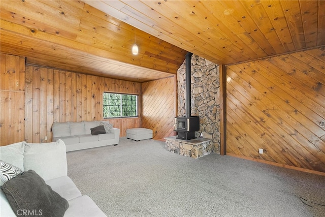 carpeted living room with wood ceiling, a wood stove, and wood walls