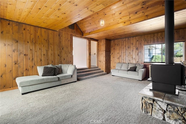 living room featuring carpet flooring, wood ceiling, a wood stove, and wood walls